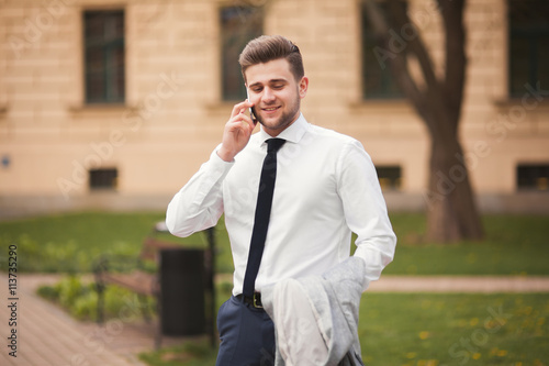 Stylish young businessman talking on the phone outdoors