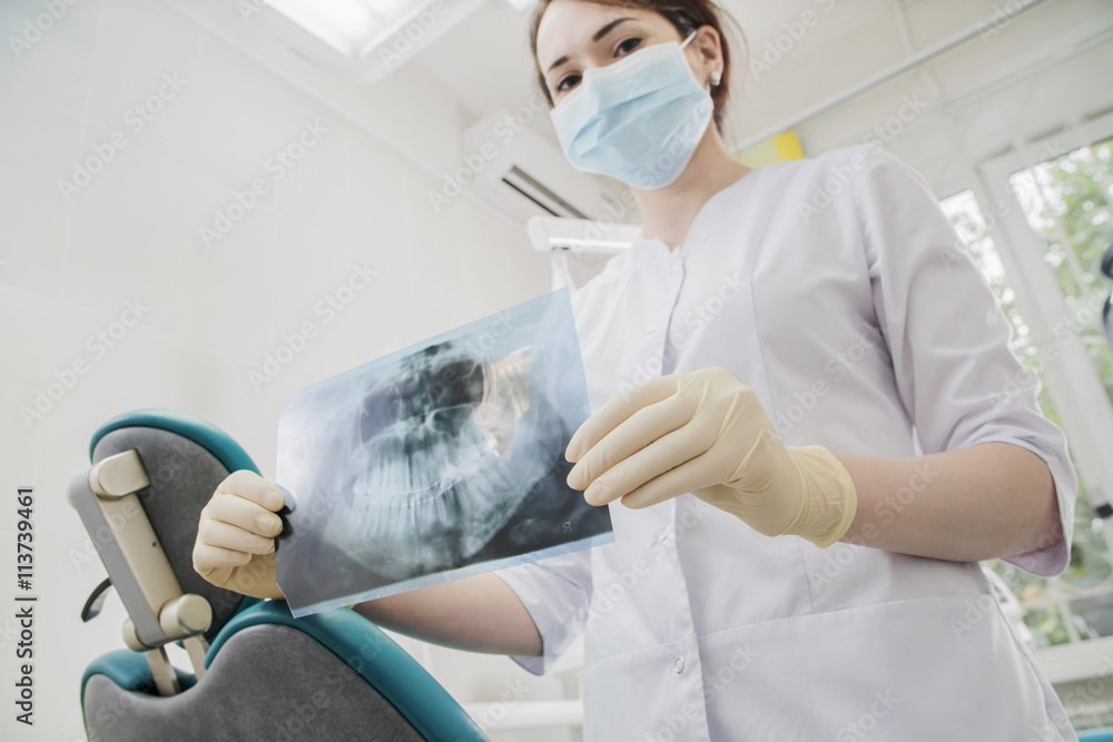 beautiful female dentist doctor, in a dental clinic. the chest x-ray of your jaw and teeth in the doctor's hands beautiful female dentist doctor, in a dental clinic. the chest x-ray of your jaw and teeth in the doctor's hands