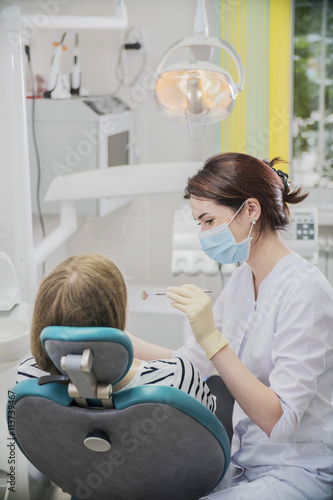 beautiful female dentist doctor  young woman doctor in a dental clinic. the dentist sits in the Cabinet beside the chair with the patient