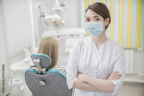 beautiful female dentist doctor, young woman doctor in a dental clinic. the dentist sits in the Cabinet beside the chair with the patient