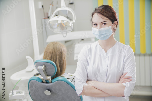 beautiful female dentist doctor  young woman doctor in a dental clinic. the dentist sits in the Cabinet beside the chair with the patient