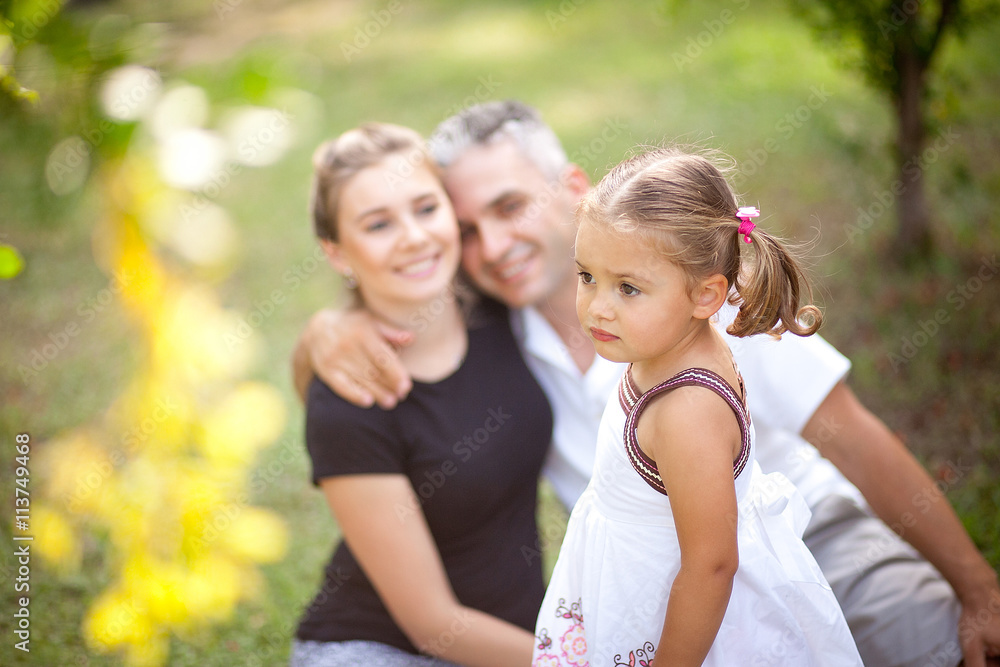 Girl than Mom and Dad upset in the background looking at her and smiling