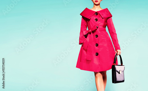 Colorful red trench coat woman with black leather handbag isolated on light blue background. Vintage retro mood fashion image. 