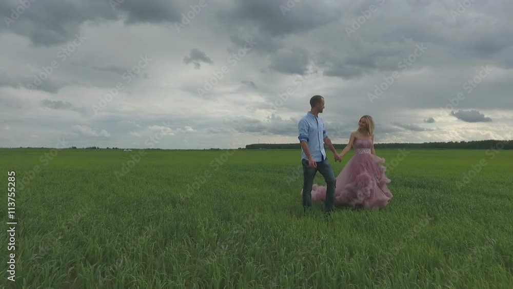 A silhouetted couple hug, kiss and then walk in a wide open field A silhouetted couple hug, kiss and then walk in a wide open field