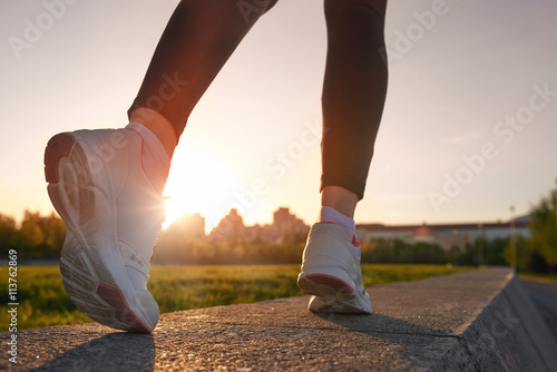 Close up of woman running shoes on sunset