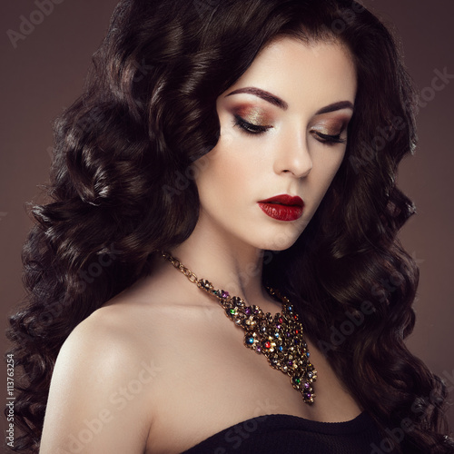 Brunette woman with curly hairstyle. Beautiful girl with long wavy hair. Perfect makeup. Fashion photo