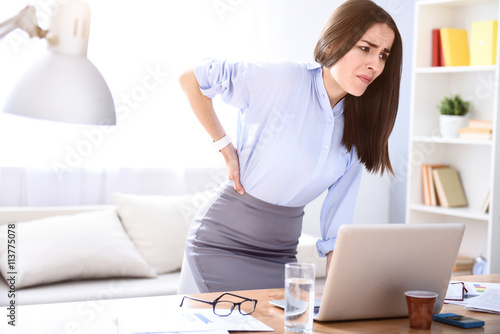 Tired sick woman standing near table