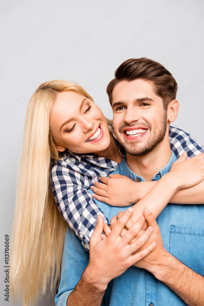 Happy cheerful man carrying his girlfriend on the back and she h Happy cheerful man carrying his girlfriend on the back and she h