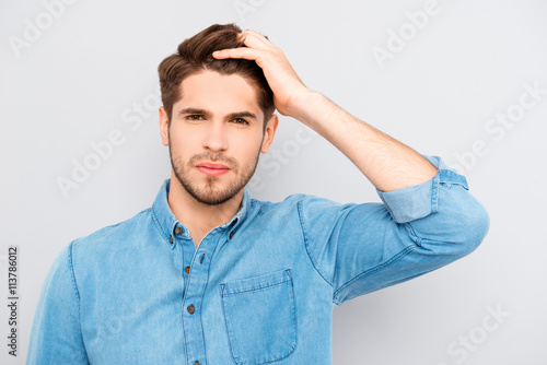 Attractive man touching his hair on gray background