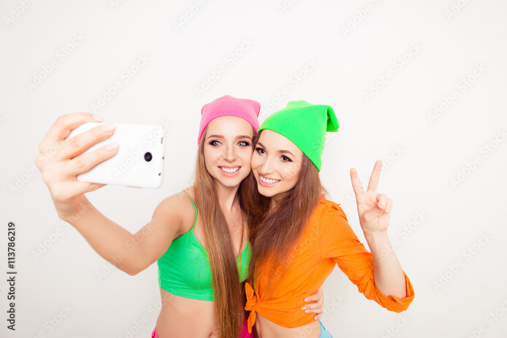 Two smiling hipster girls shooting on mobile phone Two smiling hipster girls shooting on mobile phone