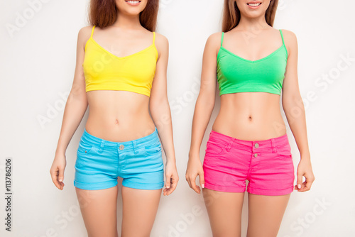 Portrait of two sexy healthy young women showing slim bellies