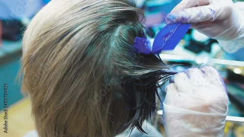 Stylist in a beauty studio does hair dye. She decided to cardinally change its image photo