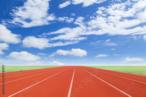 Running track with green grass and blue sky white cloud backgrou