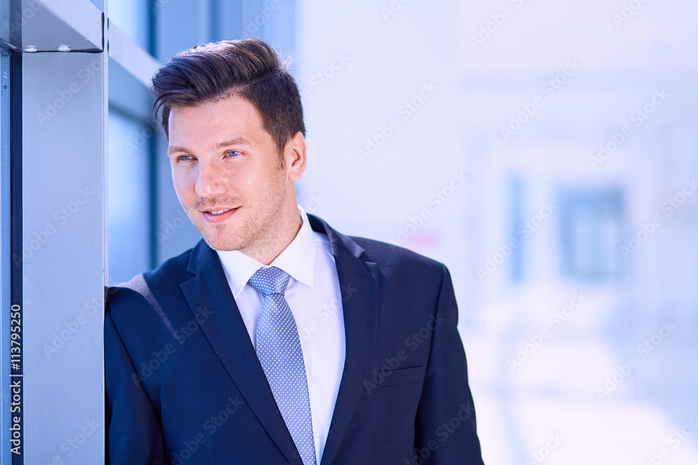 Portrait of businessman standing near window in office Portrait of businessman standing near window in office