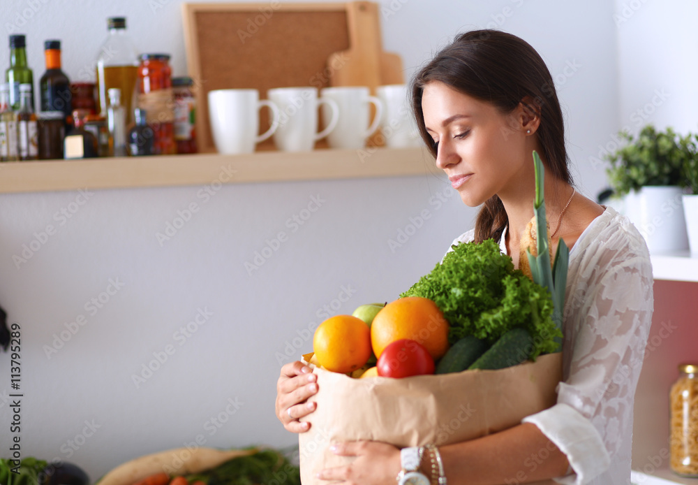 Young woman holding grocery shopping bag with vegetables Young woman holding grocery shopping bag with vegetables