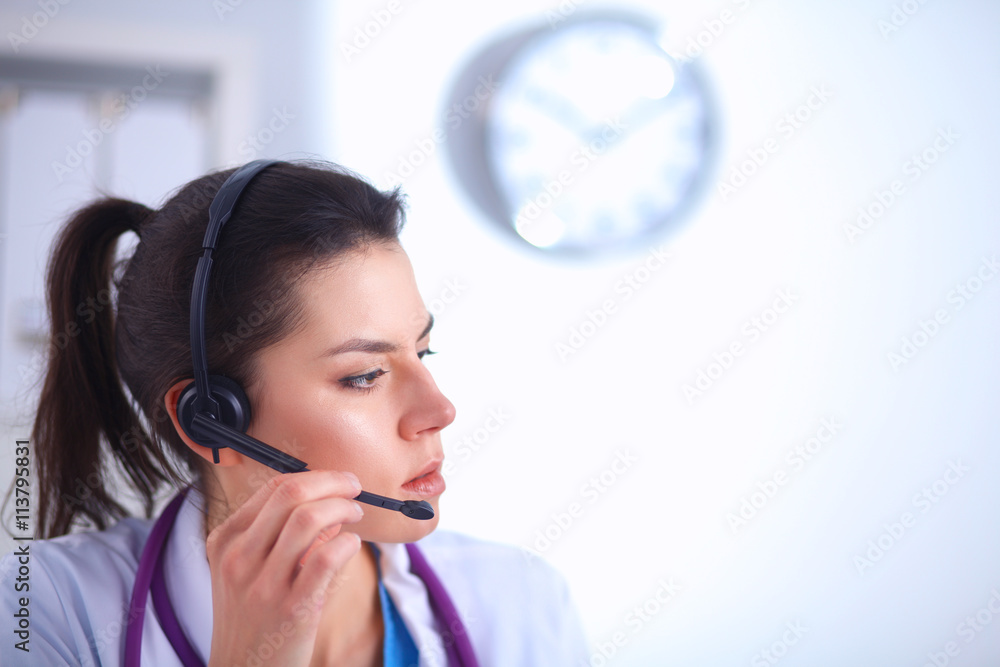 Doctor wearing headset sitting behind a desk with laptop over grey background Doctor wearing headset sitting behind a desk with laptop over grey background