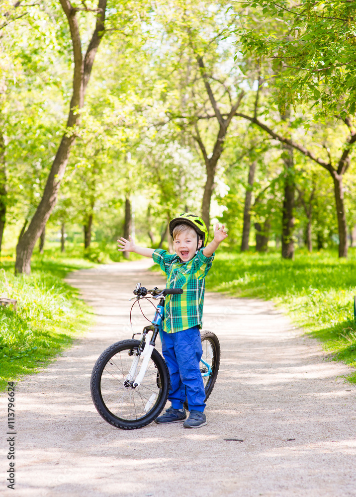 Portrait of a joyful child on a bicycle in a summer park