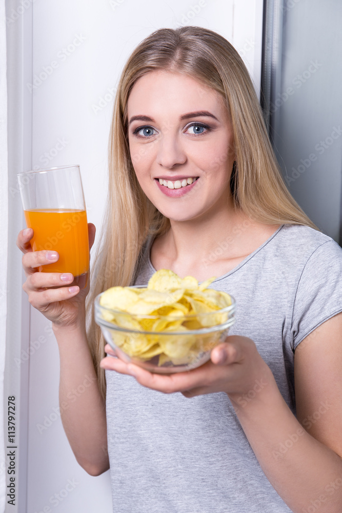 portrait of happy young woman eating chips and drinking juice portrait of happy young woman eating chips and drinking juice