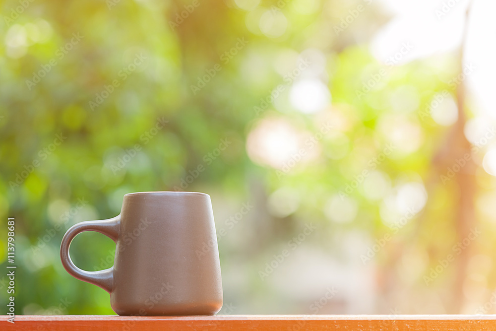 brown ceramic coffee cup with blur garden background