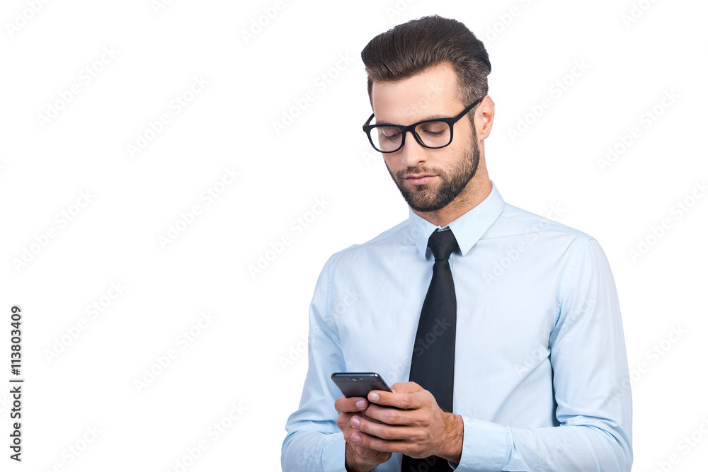 Serious young businessman in shirt and tie looking confident while using smart phone on white background Serious young businessman in shirt and tie looking confident while using smart phone on white background