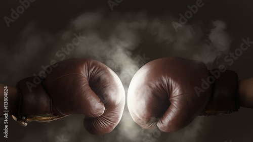 Obraz na plátně Two old brown boxing gloves hit together