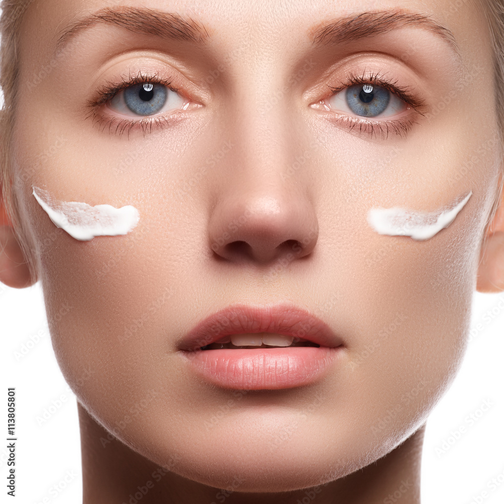 Beautiful face of young woman with cosmetic cream on a cheek. Skin care concept Beautiful face of young woman with cosmetic cream on a cheek. Skin care concept