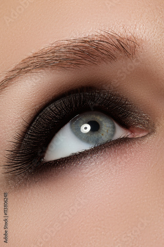 Macro shot of woman's beautiful eye with extremely long eyelashes. Sexy view, sensual look. Fashion smoky makeup.

