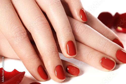 Beautiful female finger nails with red nail closeup on petals