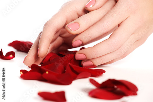 Beautiful female finger nails with pink nail closeup on petals