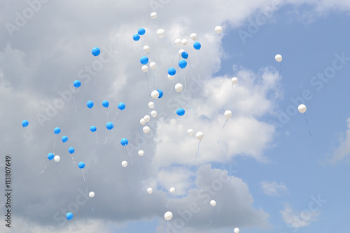 Balloons in the sky. Flying white and blue balloons in a cloudy sky.