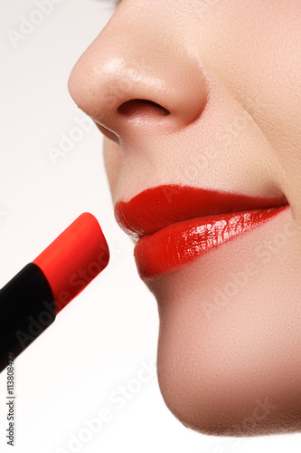 Extreme close up on model applying red lipstick. Make-up