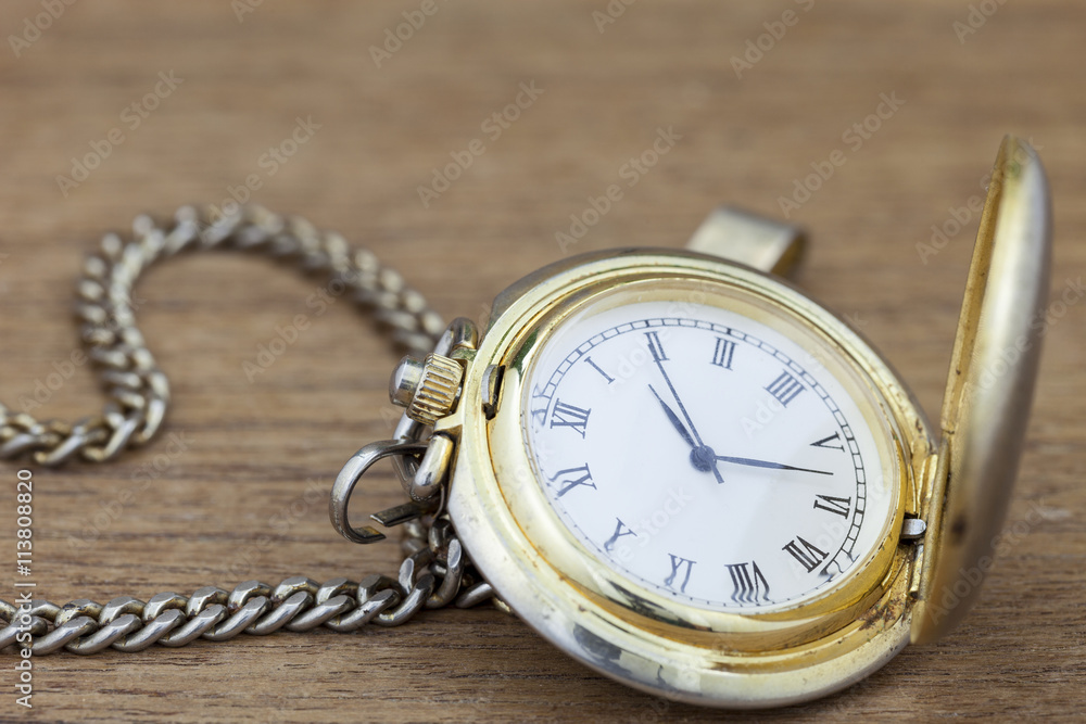 Old pocket watch on wood background.