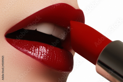 Extreme close-p on model applying dark red lipstick. Make-up