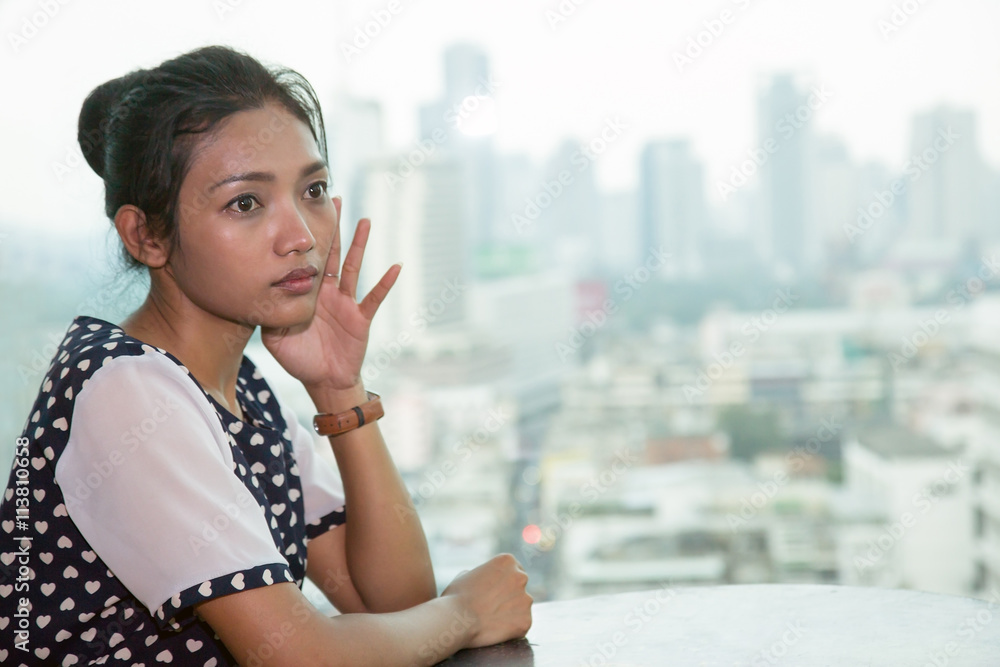 Young woman sitting at a table next to the window in a skyscraper Young woman sitting at a table next to the window in a skyscraper