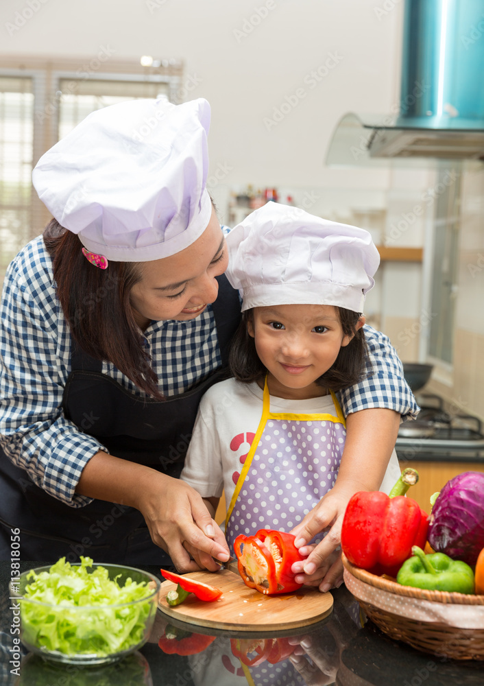 Asian mother teaching daughter making salad in kitchen,Cooking concept of happy asian little girl and mother making salad Asian mother teaching daughter making salad in kitchen,Cooking concept of happy asian little girl and mother making salad