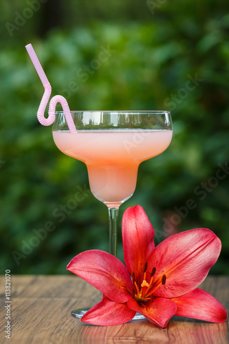 shaped glass with pink grapefruit cocktail on green background bokeh
