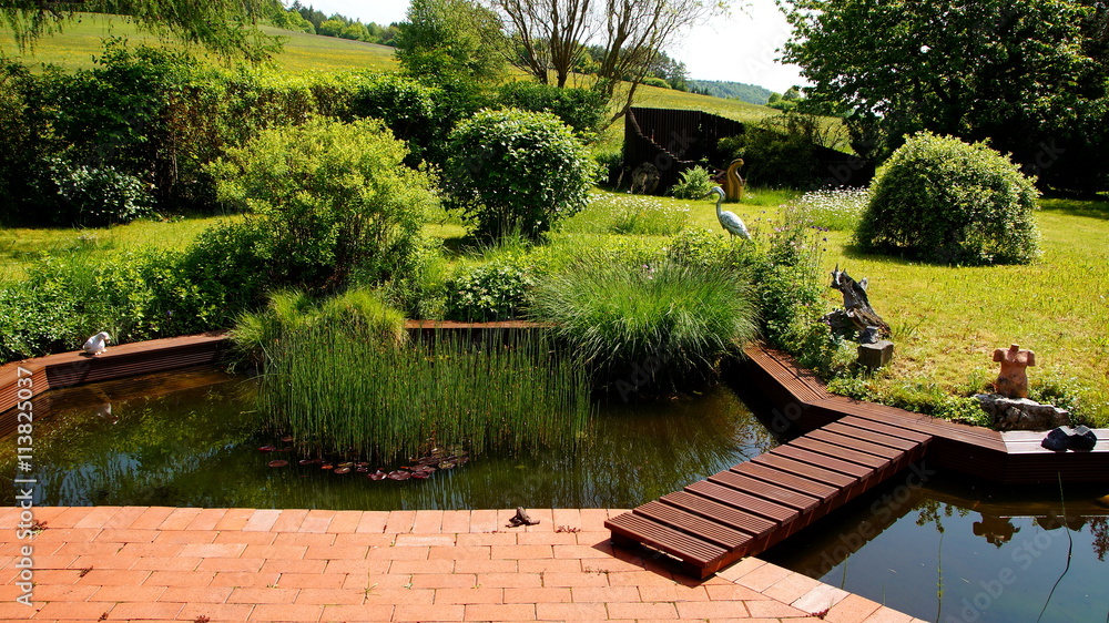 attraktiver naturbelassener Garten mit an Terrasse angrenzenden Teich