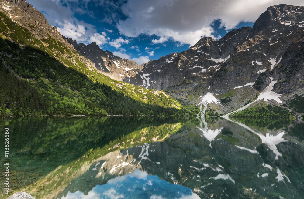 mirror reflection of mountains peaks in alpine lake