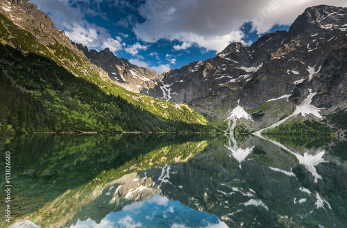mirror reflection of mountains peaks in alpine lake