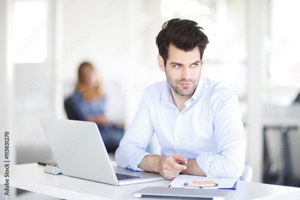 Businessman thinking about the best solution while working on laptop at office.