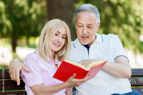 Mature couple reading a book at the park