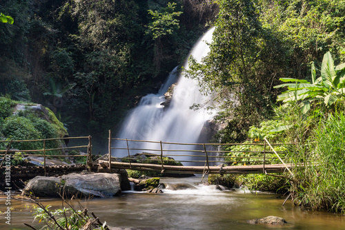 Waterfall with old wooden bridge over the river