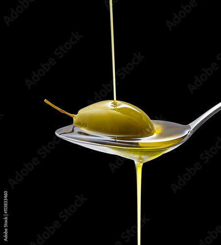 Green olive in full oil spoon on black isolated