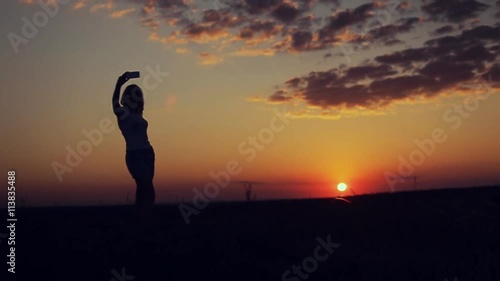 girl take selfie on sunset background on top the mountain photo