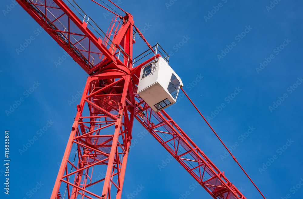 Red industrial construction crane against blue sky