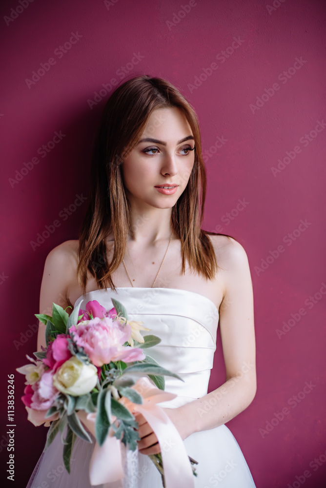 young beautiful bride with a bouquet of pink peony near the wall young beautiful bride with a bouquet of pink peony near the wall