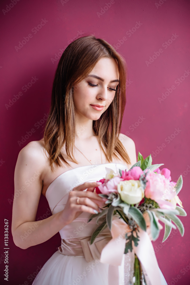 young beautiful bride with a bouquet of pink peony near the wall young beautiful bride with a bouquet of pink peony near the wall