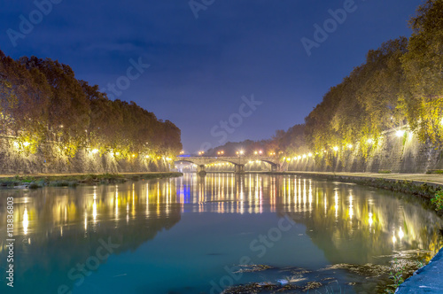 Old stone bridge on the river Tiber in Rome, lit at night