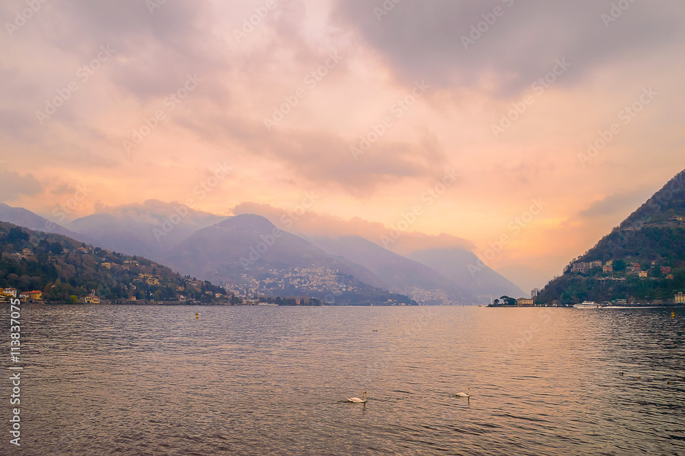 Dark cloudy sunset at lake Como, Italy, with two swans