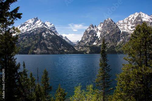 Snow Covered Grand Tetons towering over Alpine, Blue Water, Lake Jenny in Wyoming